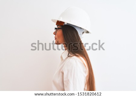 Young beautiful architect woman wearing helmet and glasses over isolated white background looking to side, relax profile pose with natural face with confident smile.