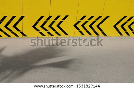 black chevrons on  yellow car park wall showing direction of flow