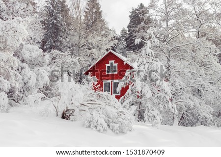 Beautiful red wooden house in snow fairy forest Sweden. House painted in traditional Swedish color. Winter scenery with red cottage surrounded by trees covered with snow and frost. Space for your text Royalty-Free Stock Photo #1531870409