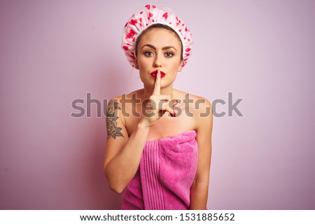Young beautiful woman wearing towel and bath hat after shower over pink isolated background asking to be quiet with finger on lips. Silence and secret concept.