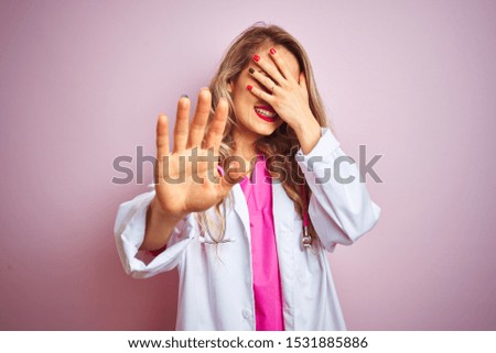 Young beautiful doctor woman using stethoscope over pink isolated background covering eyes with hands and doing stop gesture with sad and fear expression. Embarrassed and negative concept.