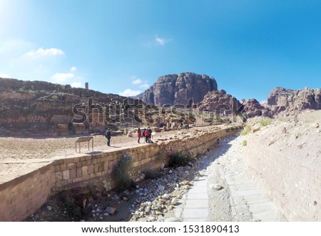 Camels and tourists walk through surreal desert landscape in old city of Petra in Jordan, panorama