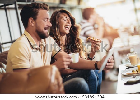 Couple eating pizza in modern cafe. They are laughing and eating pizza and having a great time.
