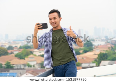 attractive and Charming man using digital smartphone technology to take photography in the city outdoor. asian handsome man in casual. Happy travel guy smiling outdoor