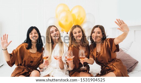 hen party. Beautiful charming women wearing in satin robe drinking alcohol and enjoying pajamas party at hotel