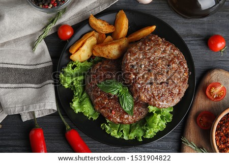 Flat lay composition with grilled meat cutlets for burger on black wooden table
