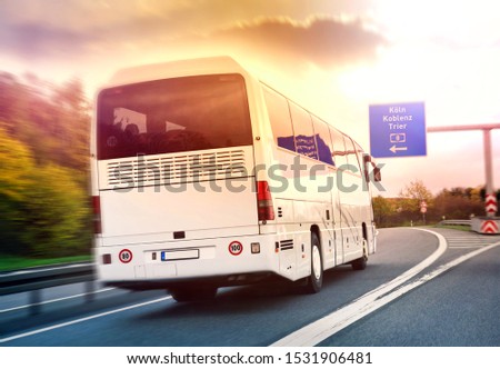Blank white bus on german highway in back light rear view with traffic signs