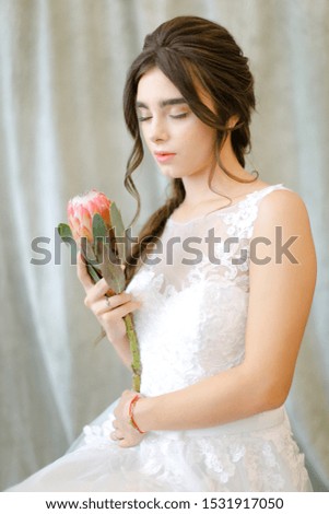 Portrait of beautiful brunette caucasian bride with flowers at studio. Concept of bridal photo session and bridal makeup.