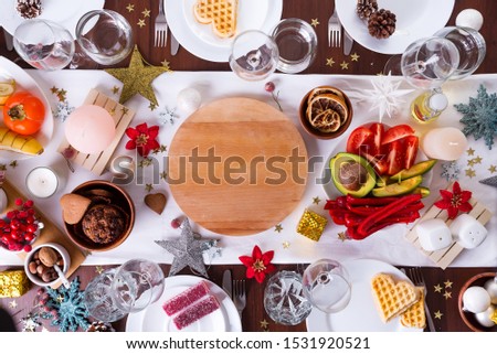 Christmas table setting with food on a plate and decoration on dark wooden table, flat lay