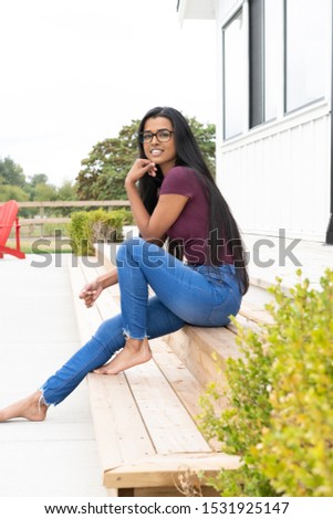 Ethnic woman lounging on the patio steps outside her suburban home