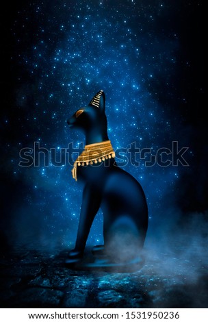 Dark night magic scene. Egyptian goddess Bastet, a statuette of a black Egyptian cat on a background of an old cobblestone road. Blue neon, moonlight at night.