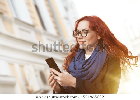 Business Woman in glasses Uses Smartphone. City with in the Background.