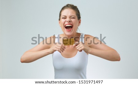 happy woman in white vest holding credit card in front of her. isolated female portrait.
