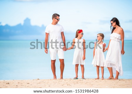 Family beach vacation. Parents with kids in white.