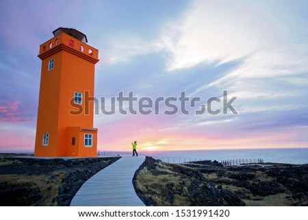 Cute child taking picture of lighthouse in lava field in beautiful nature in Snaefellsjokull National Park in Iceland, autumntime on sunset