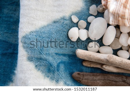 Still Life Photography Indigo dyed cloth with white sea stones and driftwood. 