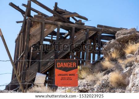Orange warning says Danger in front of wooden structure at an old abandoned mine site