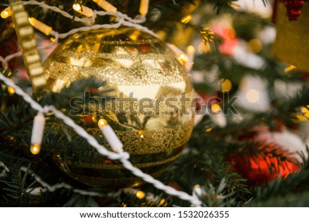 gold striped Christmas ball with sequins and garland on Christmas tree close up on blurred background bokeh, winter 
