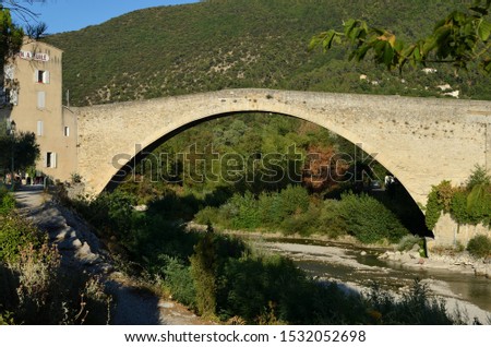 The beautiful and romantic Pont Roman in Nyons, France, in the evening sun, with the Moulin a Huile, (translation: "Oil Mill") in the distance. Drome Provencale, France
