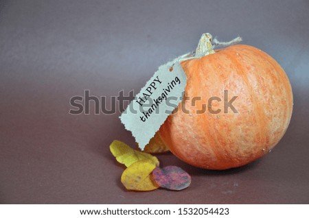 Thanksgiving Day. Pumpkin, pumpkin with autumn leaves and apples. Autumn harvest on a brown background. Happy Thanksgiving Lettering set table for celebration. fork and knife