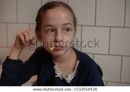 Happy teen girl eating a burger and french fries. Schoolgirl eating a burger.A girl of 9 years old has lunch after attending school with a burger.The child enjoys lunch. Schoolgirl in a school uniform