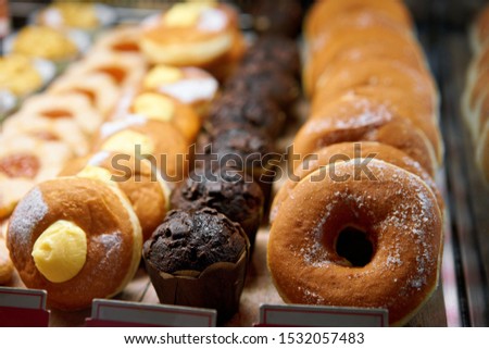 Donuts and rings. Hot pastries lie on the shelf in the cafe. Buns and chocolate muffins in the store.
