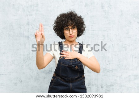 young pretty afro woman looking happy, confident and trustworthy, smiling and showing victory sign, with a positive attitude