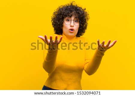 young pretty afro woman feeling extremely shocked and surprised, anxious and panicking, with a stressed and horrified look