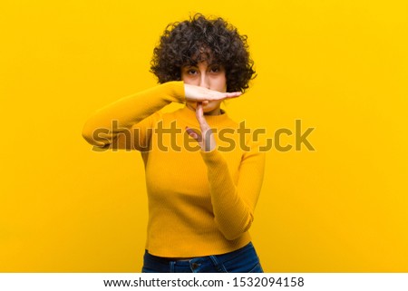 young pretty afro woman looking serious, stern, angry and displeased, making time out sign