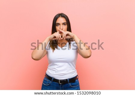 young pretty hispanic woman feeling stressed, anxious, tired and frustrated, pulling shirt neck, looking frustrated with problem against pink wall