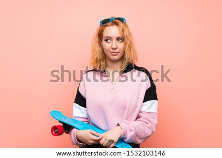 Young skater woman over isolated pink background standing and looking to the side