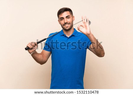Young handsome golfer man over isolated background showing ok sign with fingers