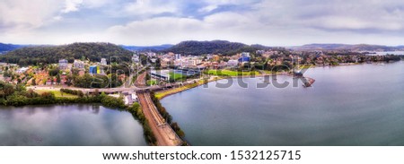 Gosford town on Australian NSW Central Coast of Pacific ocean between hill ranges at intersection of the Central Coast highway and railway line crossing Brisbane water bay - wide aerial pa Royalty-Free Stock Photo #1532125715
