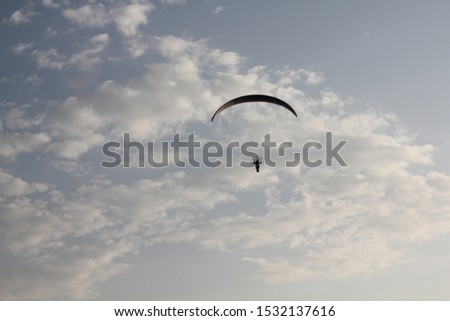 silhouette of a paraglider in the sky with clouds