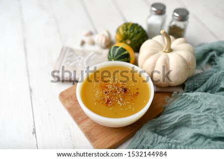 Pumpkin vegetable soup on white wooden backdrop and seasonings. Fall harvest soup