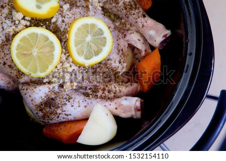 Chicken and vegetables with herbs and lemon in a slow cooker. Royalty-Free Stock Photo #1532154110