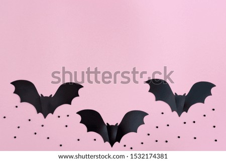 Black paper bats flying over pink colored background. Halloween and decoration concept. Flat lay with copy space. 