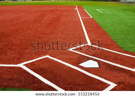The view is from behind home plate looking towards first base with artificial turf at a school softball field. The bright colors of the artificial turf are a high contrast to a normal playing field. Royalty-Free Stock Photo #153218456