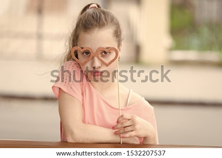 I just got invited to a valentines party. Little child looking through heart shaped goggles on valentines day. Cute kid holding fancy valentines day party props on stick. Adorable valentines girl.