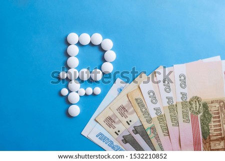Ruble sign made of round pills on blue background. Pharmacy business, medicine pill concept. 