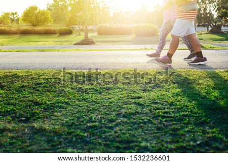 The picture focuses on the legs of two people walking and exercising together at the park where the sun shines. Because the body is not an athlete, so choose to walk before starting to run