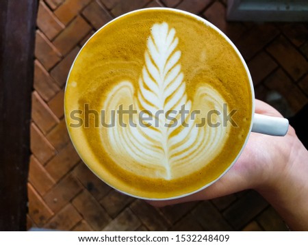 Leaf latte art on a white coffee mug  In a cafe with a warm atmosphere in Thailand
