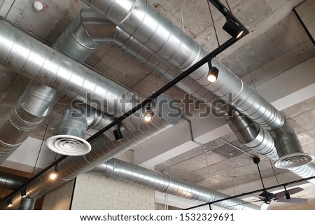 Ventilation pipes in silver insulation material hanging from the ceiling inside new building. Royalty-Free Stock Photo #1532329691