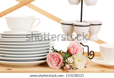 Lots beautiful dishes on wooden shelf on white background