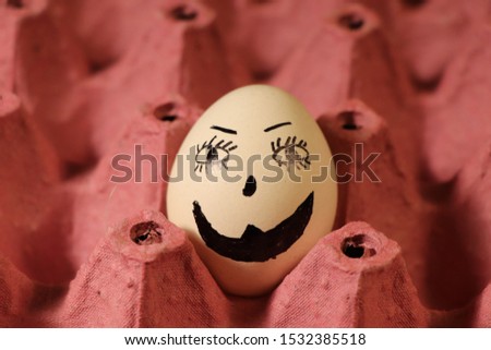 Drawing face emoji on white egg