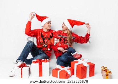 Happy family in Santa hats having fun and celebrating Christmas with gifts while sitting on a white background