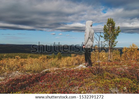 A woman in tundra enjoying scenery of colorful autumn in Norway 