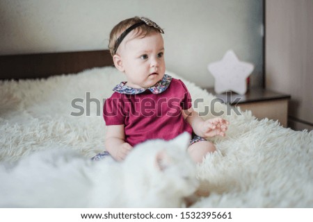 Little girl playing on the bed with her kitten. Child and cat