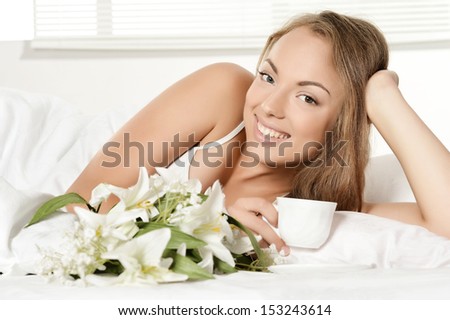 Beautiful girl in white bed drinking tea