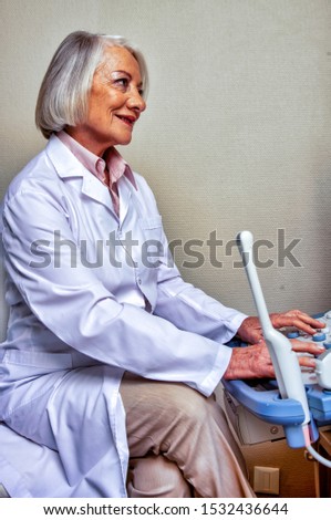 Ultrasound at hospital. Elderly female doctor confident at work.